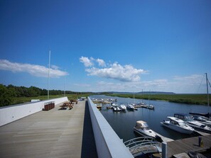 Un port de plaisance avec des bateaux amarrés, une terrasse en bois et un ciel dégagé.
