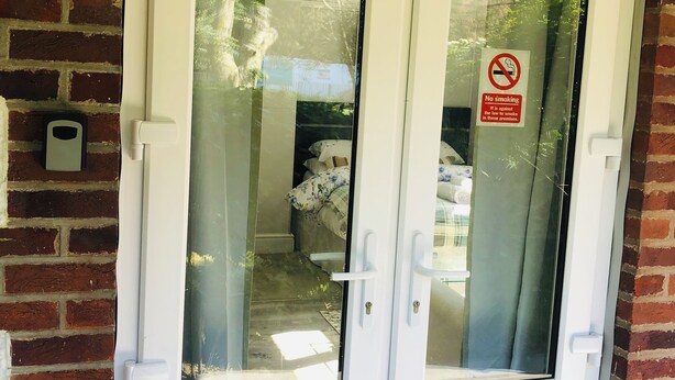 A white double door with frosted glass panels, a no-smoking sign, and a brick wall. - The studio (St Austell)
