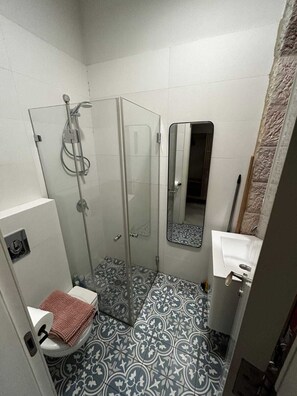 Een kleine badkamer met douche, toilet en wastafel.