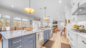 A spacious kitchen with a large island, modern appliances, and pendant lighting. - Pier Cove Estate - Pool, Pickleball, Hot Tub, Firepit - Sleeps up to 23 (Fennville)