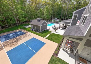 A backyard with a swimming pool, a tennis court, and a covered patio area. - Pier Cove Estate - Pool, Pickleball, Hot Tub, Firepit - Sleeps up to 23 (Fennville)