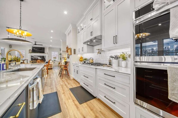 A modern kitchen with white cabinetry, a large island, and a built-in oven.