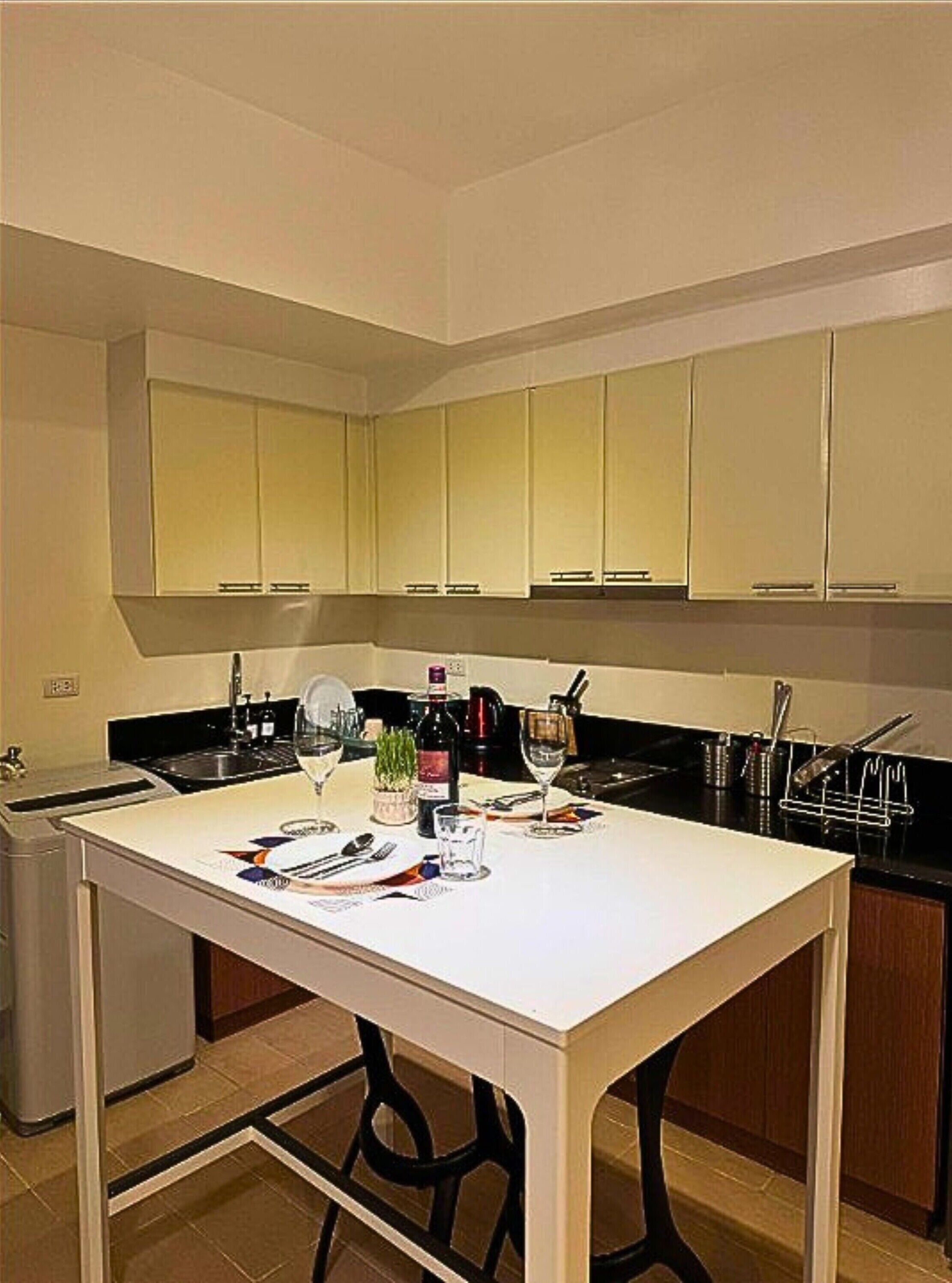 A modern kitchen with white cabinets, a black countertop, and a white table set for dining.