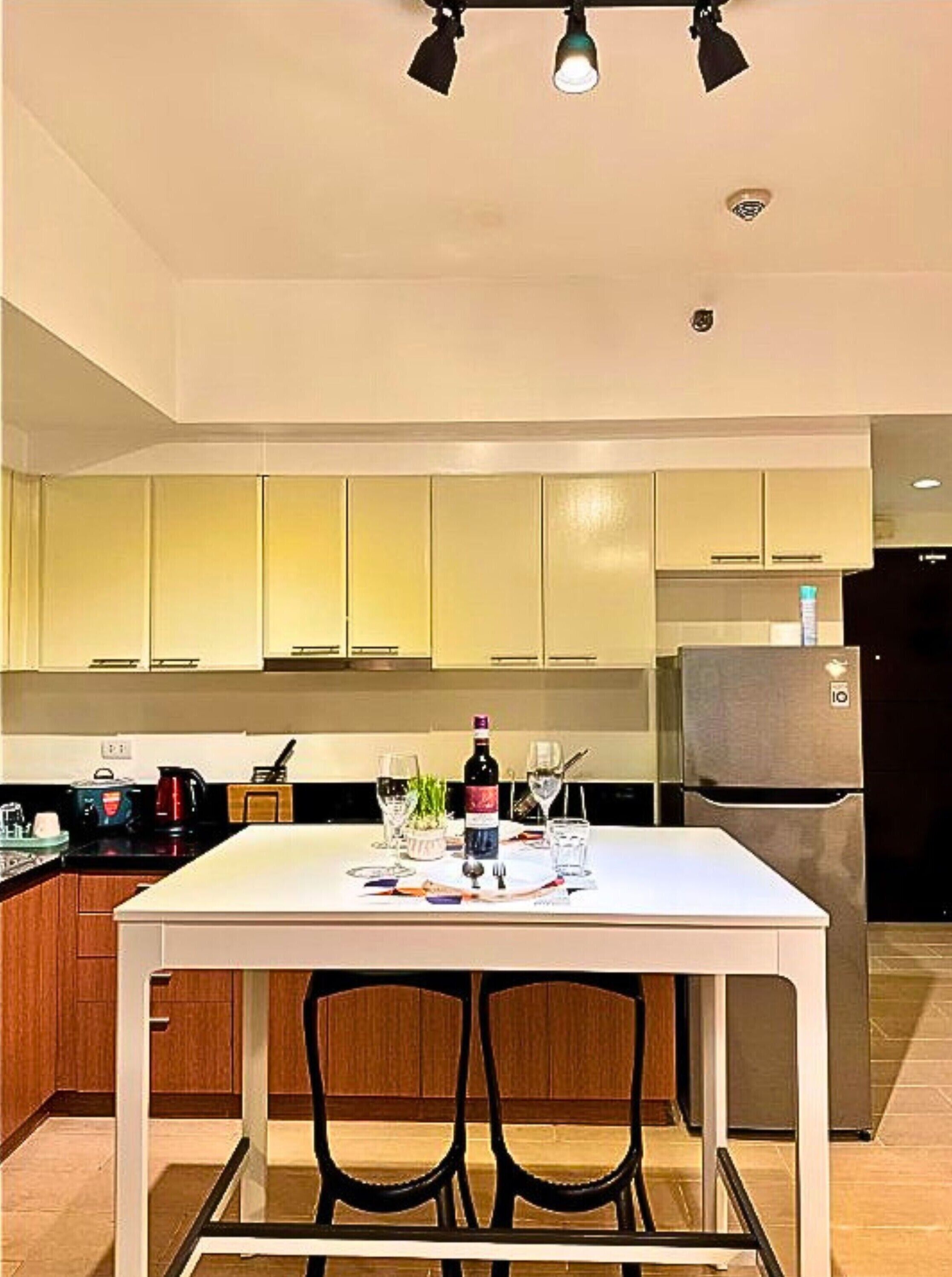 A modern kitchen with a dining table, chairs, and a refrigerator.
