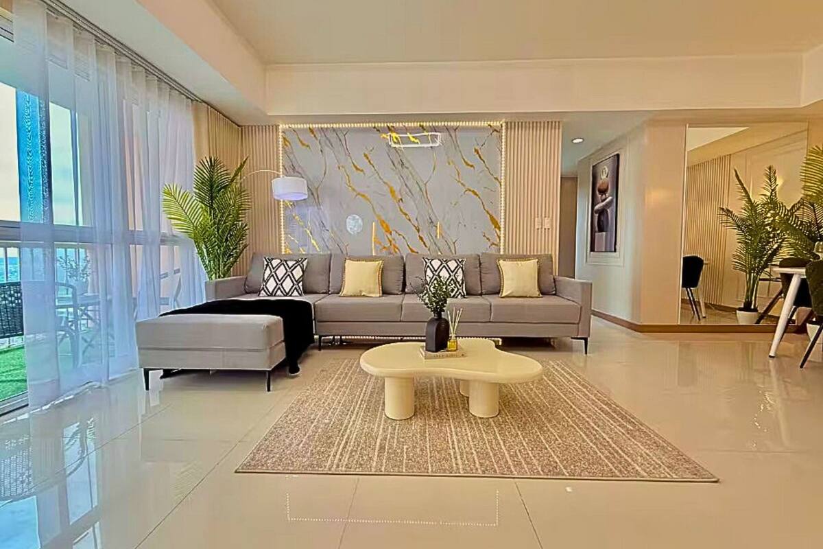 A modern living room with a grey sofa, a round coffee table, and a marble-patterned wall.