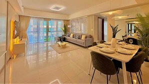 A modern living room with a dining area, large windows, and a sofa.