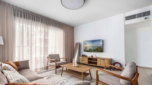 Una sala moderna con un sofá, una mesa de centro, un televisor y un aparador de madera.