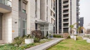 Un edificio de apartamentos moderno con entrada cubierta, jardín ajardinado y un camino.