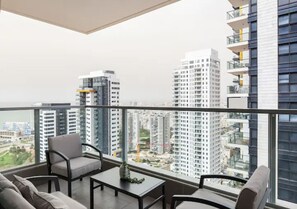 A balcony with a city view, furnished with a sofa, chairs, and a small table.