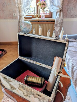 Ein offener Vintage-Koffer mit Kerzen, einem Globus und einem roten Buch.