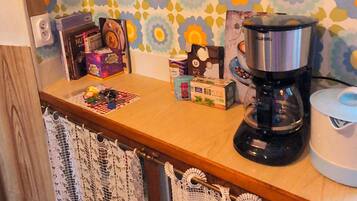 A kitchen with a coffee maker, a kettle, and various kitchen items on the counter.