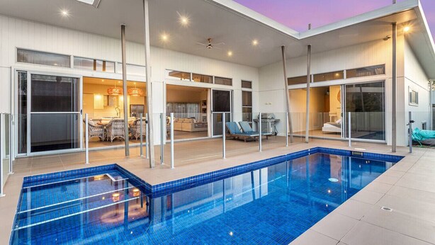 Una casa moderna con piscina, puertas de cristal grandes y un área de patio.
