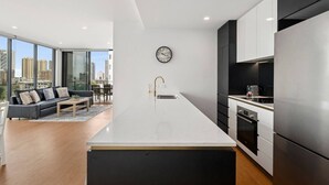 A modern apartment with a large kitchen, a dining area, and a living room with a view of the city. - Skyline Serenity - Modern Escape + Stunning Views (Surfers Paradise)