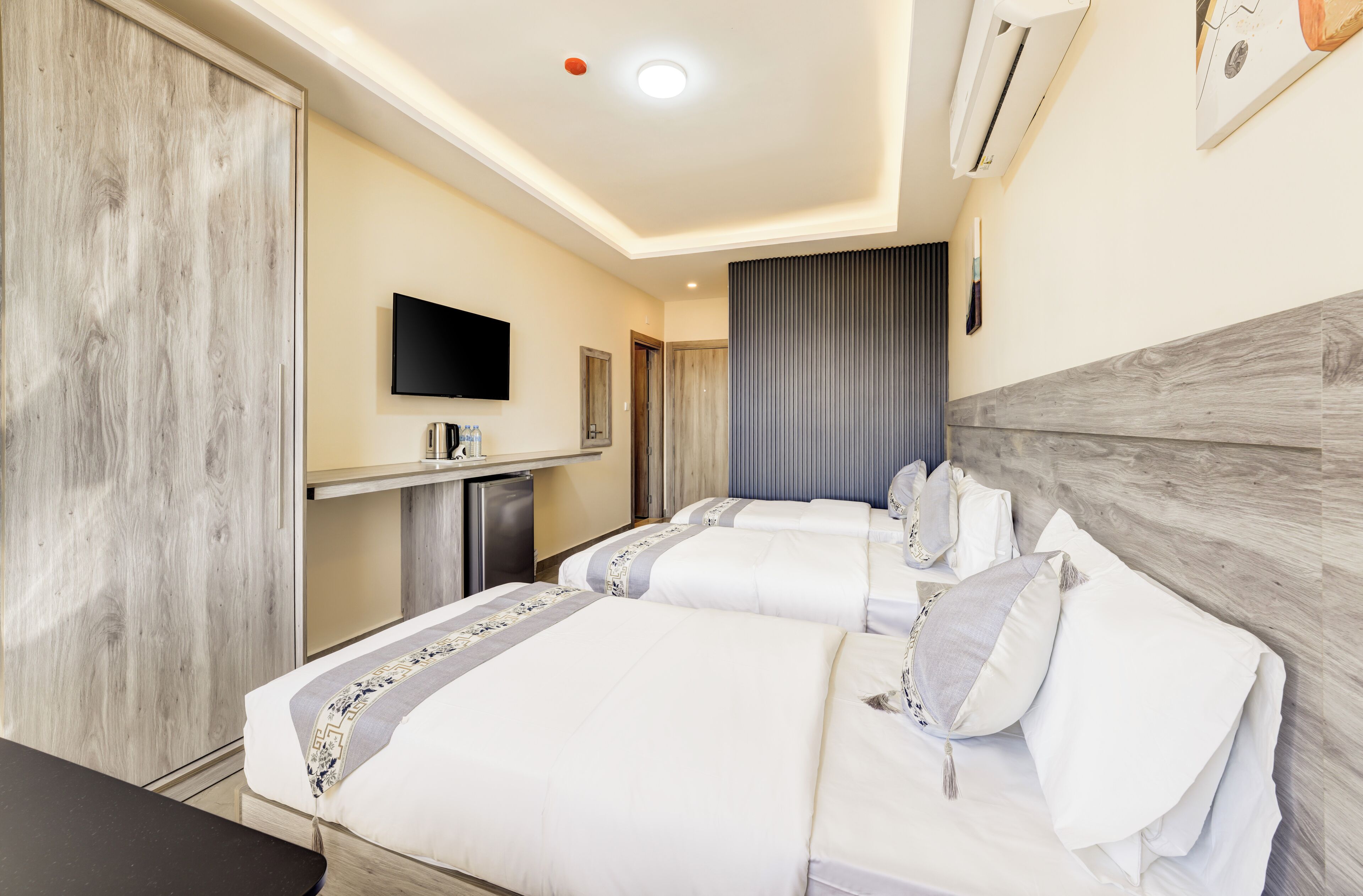 A hotel room with two beds, a TV, a desk, and a wardrobe.