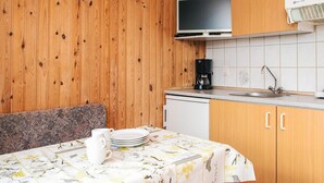 Cocina compacta con paredes de madera, televisor integrado, cafetera y lavabo.