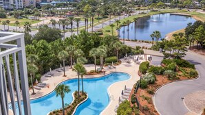 A resort with a large pool, palm trees, and a view of the city skyline.