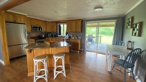 A spacious kitchen with wooden cabinets, a large island with stools, a refrigerator, and a dining area with a table and chairs.