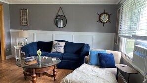 A living room with a blue sofa, a round coffee table, and a white armchair.