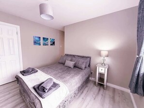 A bedroom with a bed, a bedside table with a lamp, and a door. - 3BR Modern House, Garden, Parking, Sleeps 6, Wifi (Strabane)