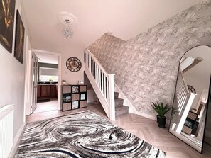 A staircase with a floral wallpaper, a mirrored wall, and a herringbone-patterned rug. - 3BR Modern House, Garden, Parking, Sleeps 6, Wifi (Strabane)