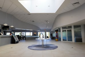 A spacious lobby with a high ceiling, a central round table, and a reception desk. - Bright 3B w/ Pool Close to Disney @ Encantada 8545 (Kissimmee)