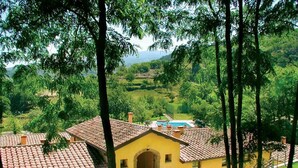 A yellow building with a tiled roof, surrounded by greenery and a swimming pool. - Apartment 5 (Castel del Piano)