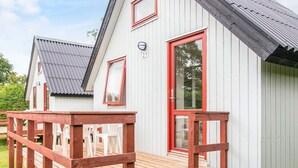 A small, single-story building with a red door and windows, a wooden deck, and a number '21' sign. - 6 Person Holiday Park Home in Grindsted (Grindsted)