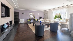 Un salon moderne avec un parquet en bois foncé, un grand ensemble de canapés, une table basse et une cheminée.