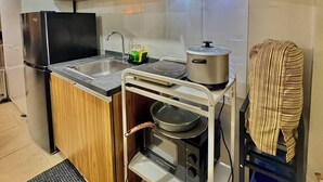 A compact kitchen with wooden cabinets, a built-in stove, a sink, and a microwave. - Cozy Condo @ Paranaque near NAIA (Paranaque City)