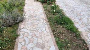 Un sendero de piedra que conduce a una entrada protegida por una reja de metal.