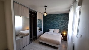 Un dormitorio con una cama, un armario, un espejo y una pared con un diseño ondulado.