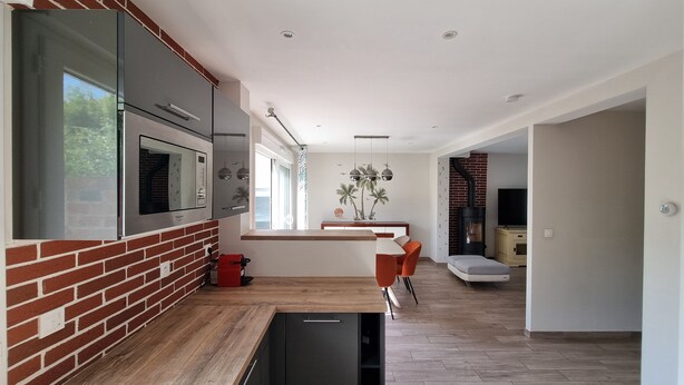 Una cocina moderna con pared de ladrillo, electrodomésticos integrados y encimera de madera.