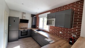 Una cocina moderna con pared de ladrillo, electrodomésticos de acero inoxidable y encimera de madera.