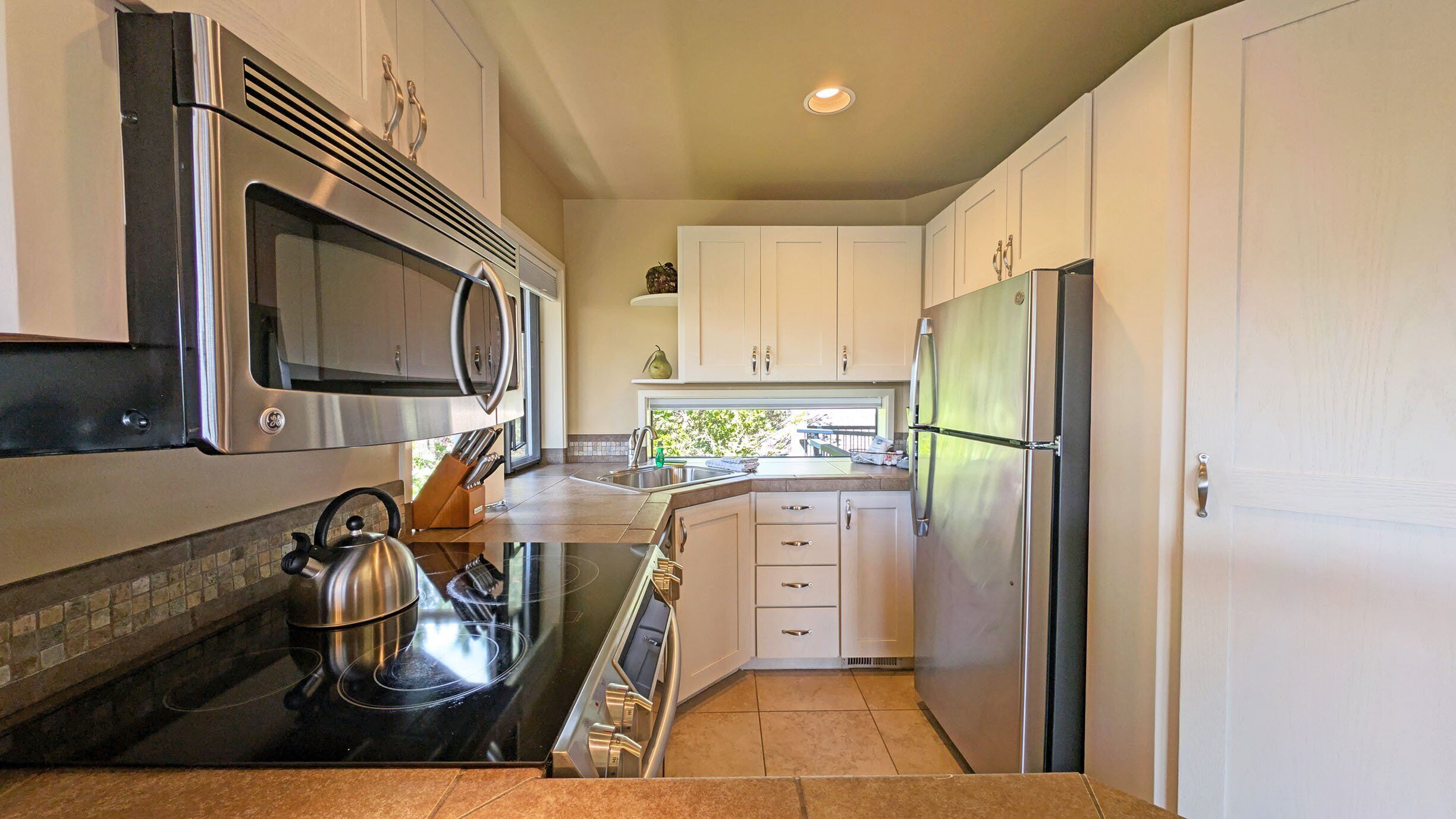 A modern kitchen with stainless steel appliances, white cabinets, and a tiled backsplash.