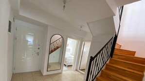 A staircase with wooden steps and black railings, leading to a bedroom with a bed and a window. - Mitra apart (Antalya)