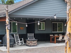 Un área de patio al aire libre con una parrilla, asientos y luces colgantes.