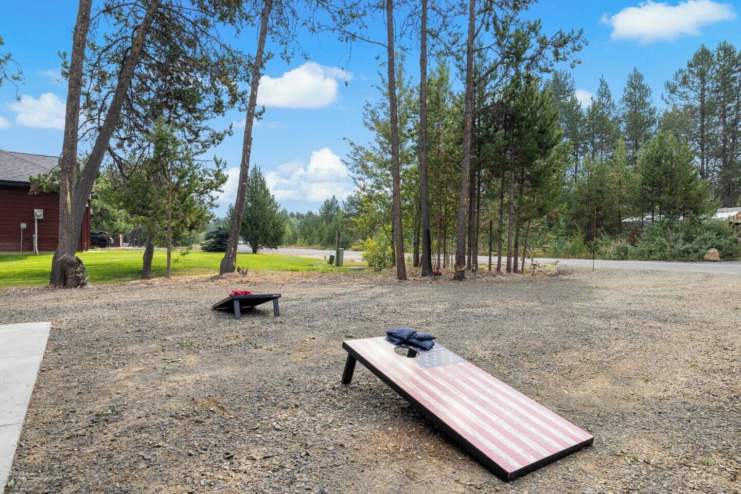 Un espacio al aire libre con una mesa de picnic, un banco y un edificio rojo al fondo.