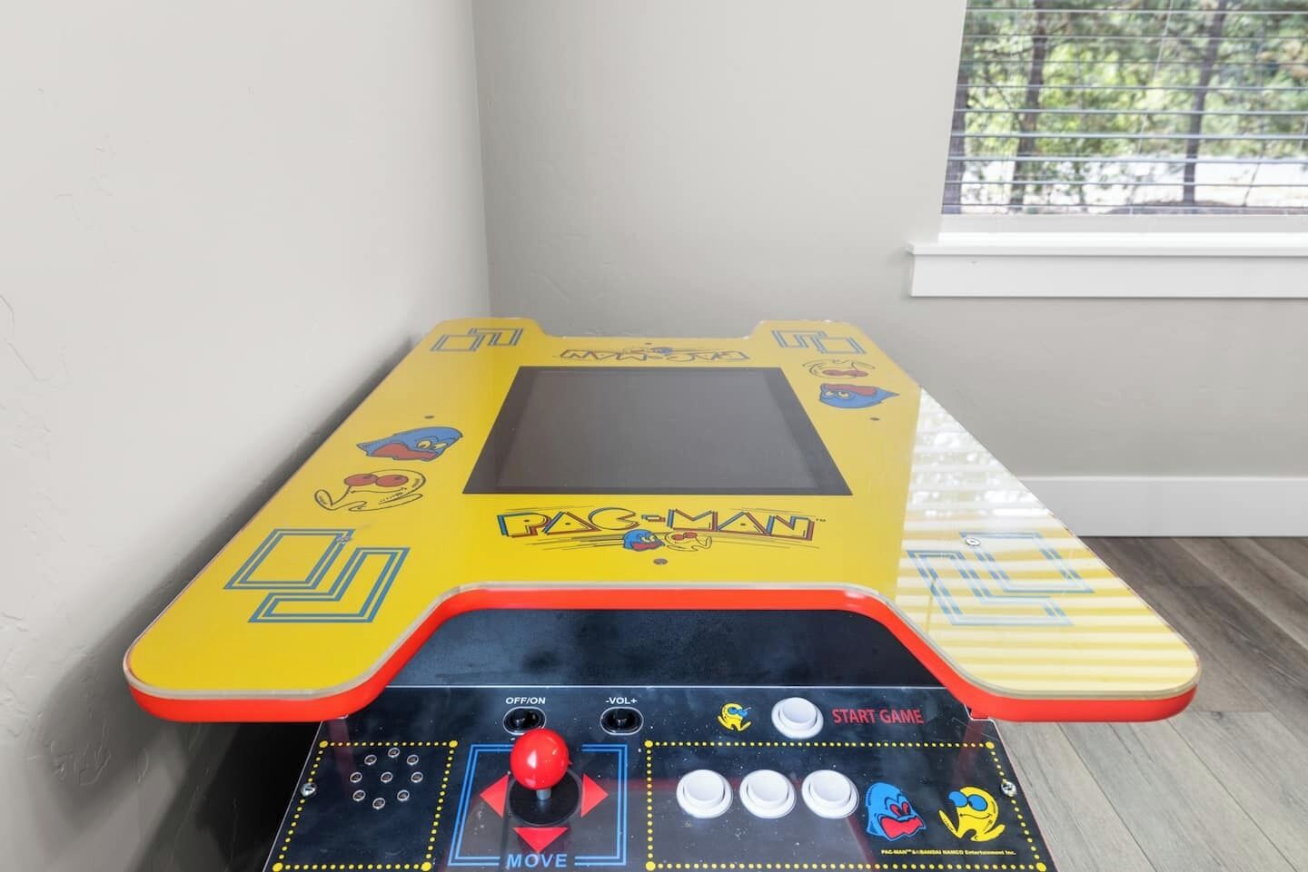 Un juego de Pac-Man en una sala con una ventana y una mesa a rayas.