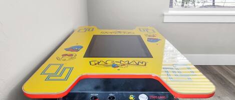 Un juego de Pac-Man en una sala con una ventana y una mesa a rayas.