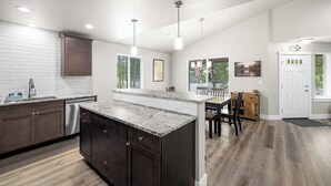 A modern kitchen with dark wood cabinets, a granite island, and pendant lighting.