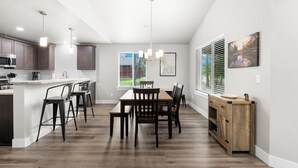 A modern kitchen with a central island, bar stools, and a dining table with chairs.