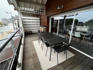 Un espacio exterior techado con zona de comedor, una mesa y sillas, una parrilla y vistas a la calle.
