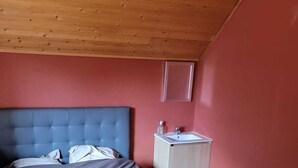 Ein Schlafzimmer mit einem Bett, einem Nachttisch und einer Holzbalkendecke.