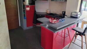 Eine kompakte Küche mit einer roten Kochinsel, einer Mikrowelle, einem Herd und einem Toaster.