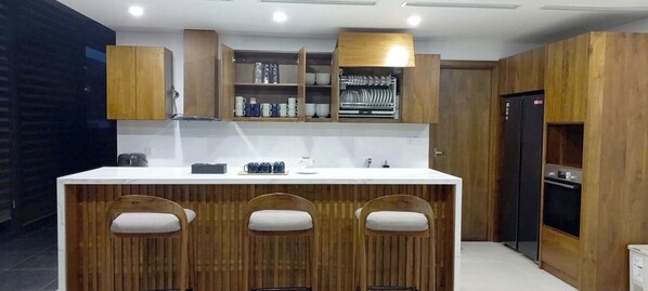 A modern kitchen with a central island, wooden cabinets, and built-in appliances. - Navilla Hue Homestay (Hue)