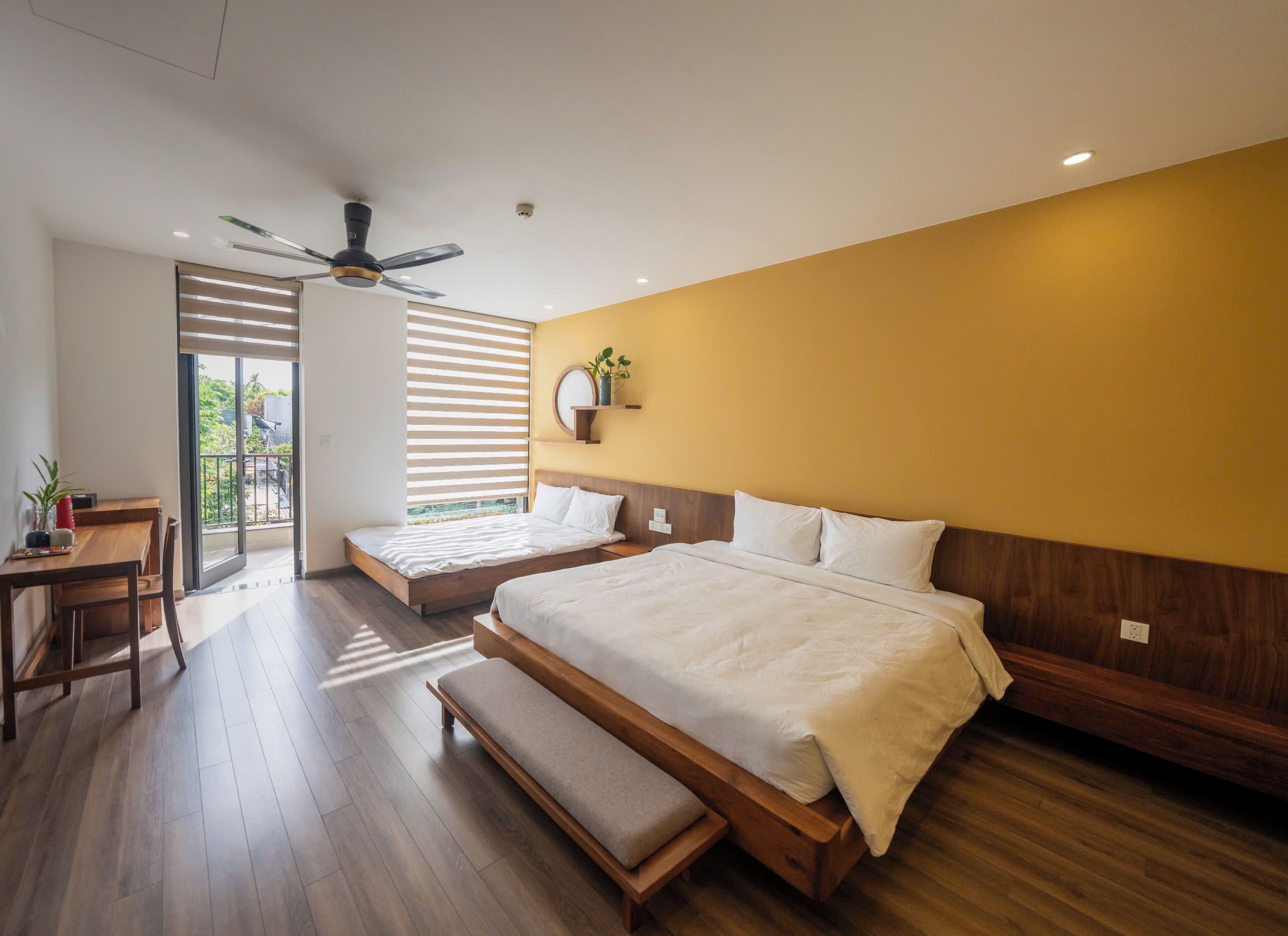 Une chambre à coucher moderne avec un grand lit, un bureau et un ventilateur de plafond.