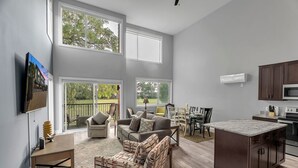 A spacious living area with a large window, a dining table, and a kitchen with dark cabinets and a marble countertop. - Opulent Birmingham Retreat (Birmingham)