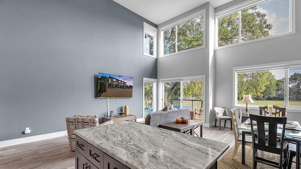 A modern kitchen with a marble countertop, a dining area with a table and chairs, and large windows offering views of the outdoors. - Opulent Birmingham Retreat (Birmingham)