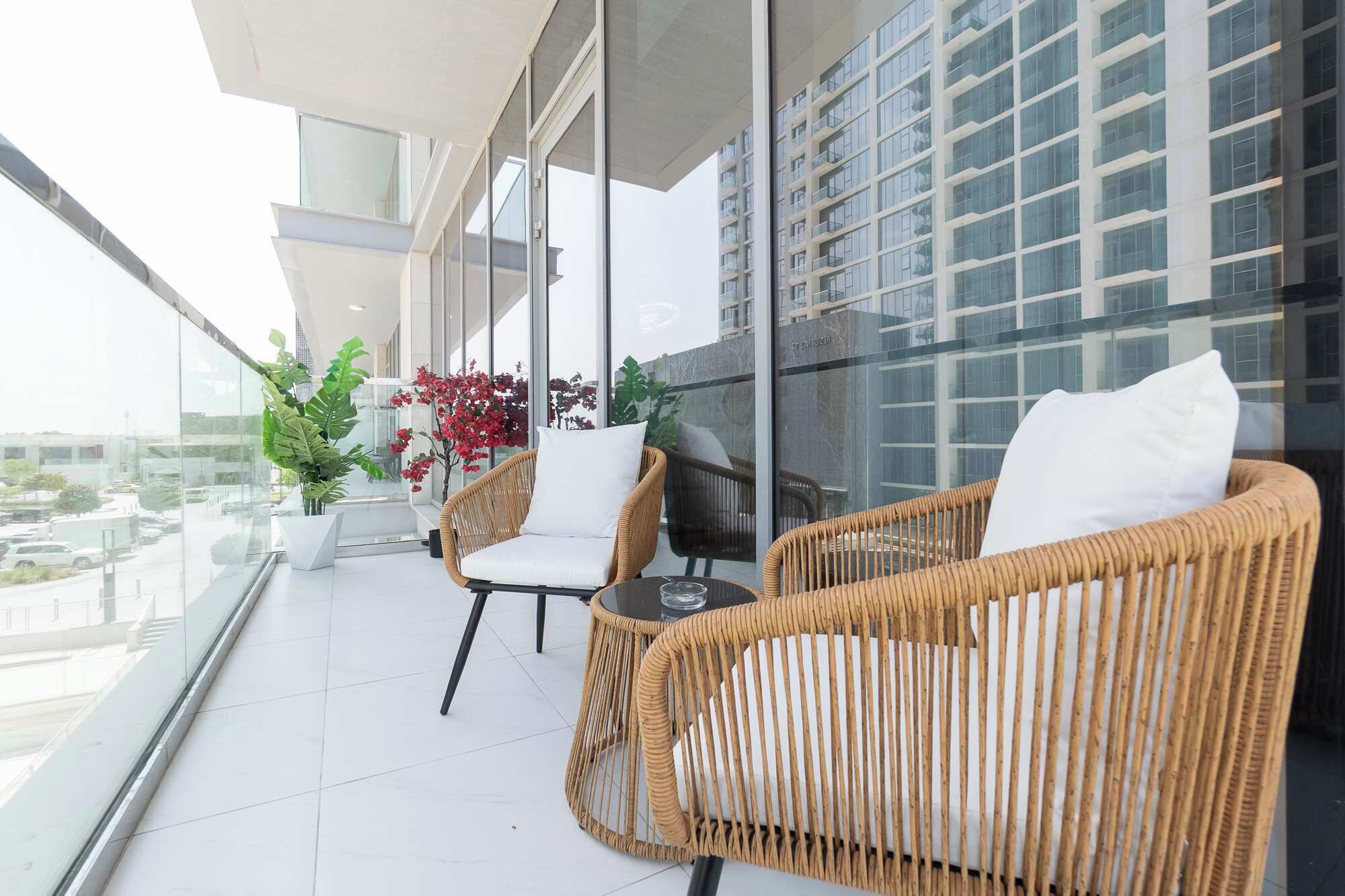Un balcone con mobili in vimini, piante in vaso e vista su un edificio moderno.
