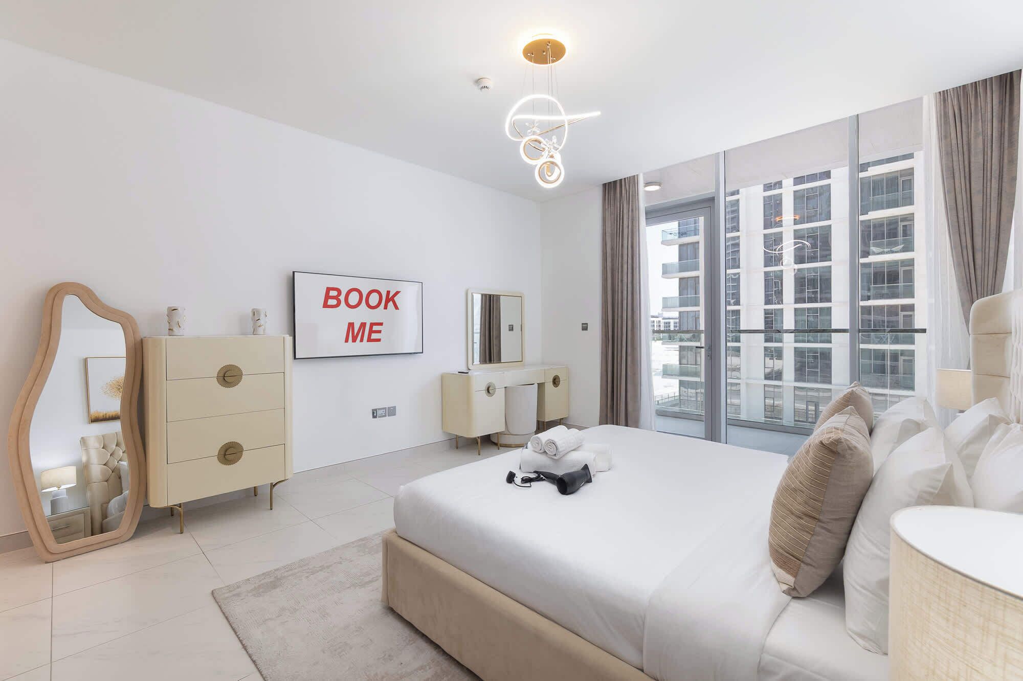 Una habitación de hotel moderna con una cama grande, una tocador con espejo, un aparador y un cartel en la pared que dice 'BOOK ME'.